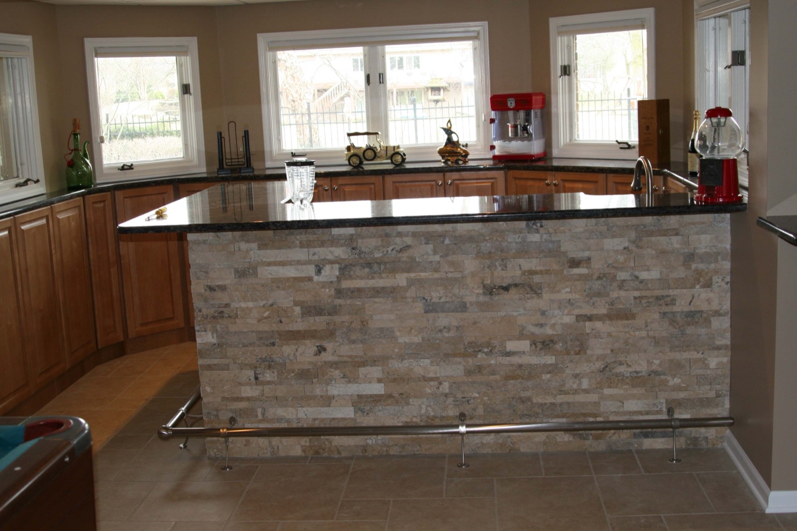 Custom kitchen island with stacked-stone base and granite countertop, surrounded by maple cabinetry